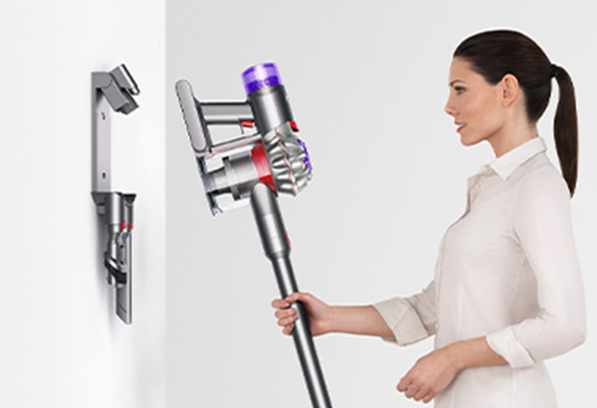 Απεικονίζεται μια γυναίκα να τοποθετεί τη σκούπα στη βάση στήριξης.